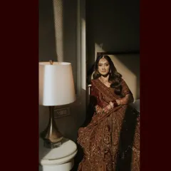 An artistic and moody portrait of the bride, Harita, in her stunningly detailed lehenga. The play of light and shadow adds a touch of drama and elegance to this Mumbai wedding shot.