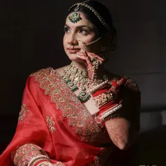 A moment of quiet reflection. This artistic bridal portrait uses dramatic side lighting to highlight the bride's features, her intricate jewelry, and the rich color of her saree.