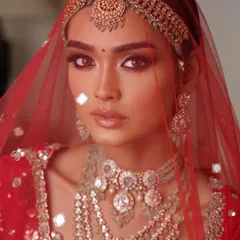 A close-up of a classic red bridal look. The focus is on the eyes, with a sharp wing and soft smoke, paired with a perfectly defined lip. The skin is kept fresh to balance the richness of the attire.