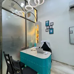 The doctor's consultation desk, featuring a vibrant teal base and a modern ring chandelier. This area is designed to be approachable and professional, with integrated storage and a clean, glossy tabletop for a clutter-free workspace.