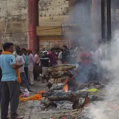 Mourners and onlookers gather around a funeral pyre on the ghats. This frame shows the public, communal nature of these final rituals in Banaras.