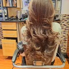 This angle shows the beautiful cascade of layers and curls from the back. This is a timeless salon blowout style.