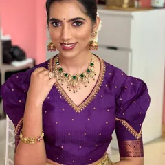 A close-up of the model in her festive attire. The green kundan necklace adds a beautiful pop of color.