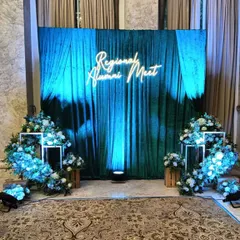 For this regional alumni meet, I designed a sophisticated stage with a rich green velvet curtain and a custom neon sign. The blue uplighting and floral arrangements create a premium and memorable atmosphere for formal gatherings.