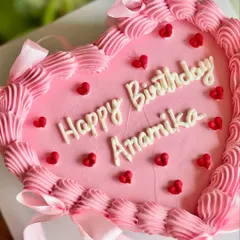 A pretty-in-pink heart cake for a birthday celebration. This design features a piped border, tiny red hearts, and delicate pink ribbons tied into bows.