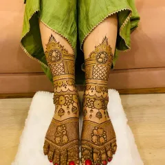 A complete bridal look includes detailed foot mehandi. This design features symmetrical patterns with fine lines and traditional motifs that extend from the toes to the ankles, perfectly complementing the hand designs.