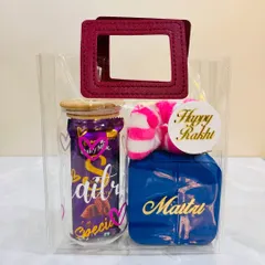 This special Rakhi hamper for a sister comes in a clear tote bag. It includes a personalized glass tumbler, a custom jewelry box for her treasures, a scrunchie, and of course, chocolate.