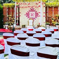 The complete guest seating arrangement for the outdoor Seemantham ceremony. We provided chairs with clean white covers and maroon sashes, which complemented the red patterned carpet and the main stage decor.