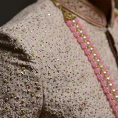 A close-up of the shoulder and collar of the off-white sherwani, showing the intricate threadwork and subtle sequin details.