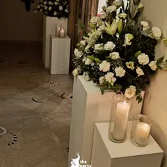 I used modern white pedestals of varying heights to display large bouquets of white lilies and carnations, adding a touch of contemporary style to the classic floral arrangements.