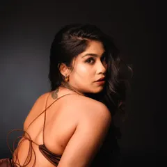 This back-profile shot in the studio highlights the elegant design of the dress and the model's pose. The dramatic lighting creates a sense of mystery and sophistication.
