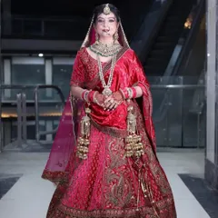 A regal bride in a deep red velvet lehenga. This outfit features elaborate embroidery on the skirt and blouse, paired with a full set of bridal jewellery, perfect for a traditional wedding ceremony.