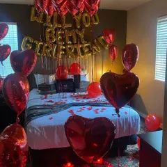 A sweet and direct way to ask, this room is filled with red heart balloons and a "Will You Be My Girlfriend" banner for a memorable proposal.