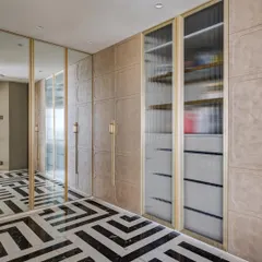 This premium walk-in area features a mix of mirrored, textured, and fluted glass wardrobe doors. The monochrome inlay flooring adds a bold graphic element to the luxurious space.