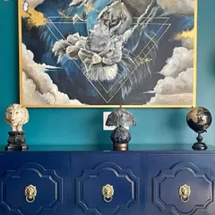 The intense gaze of the lion, captured in this acrylic painting. The artwork is framed and placed above a beautiful navy blue credenza, demonstrating how a custom piece can elevate an interior space.