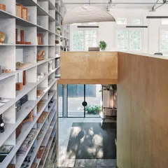 The double-volume space in our studio features a floor-to-ceiling grid of marble shelves. This element is both functional for storage and instrumental in breaking down the scale of the large space.