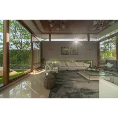 We designed this living room with a floating roof and expansive glass walls to create a space that feels boundless, inviting sunlight and the surrounding greenery indoors.