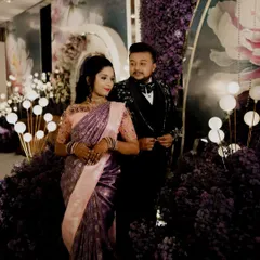 A dramatic and elegant portrait of the couple at their reception, surrounded by a lavish purple floral decor.