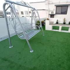 A close-up of the garden swing on the new rooftop lawn. The artificial turf provides a soft and durable surface that stands up to furniture and foot traffic.