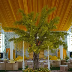 A magnificent 'tree of life' centerpiece with delicate yellow flowers, set against a draped yellow ceiling, created a focal point for the Haldi function.