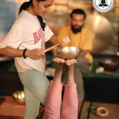 A student practices foot reflexology with a singing bowl on her partner. This hands-on learning helps you understand the technique's power to ground energy and promote deep relaxation.