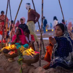 On the riverbank, a family performs Chhath Puja rituals with offerings and diyas, showcasing the communal aspect of this important Bihari festival.
