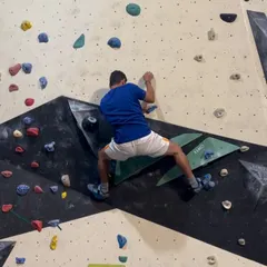 A climber carefully plans his next move on a geometrically complex section of our bouldering wall. Every route is a new puzzle to solve.