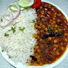 A plate of my classic Chole Chawal, a favorite for any community feast. I serve it with fluffy basmati rice and a fresh salad, making it a complete and satisfying meal for your guests.