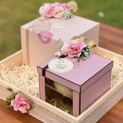 Bespoke return favours designed to share sweetness. These gift boxes, presented in a rustic wooden tray, feature our signature pink packaging, floral toppers, and custom tags, creating a warm and inviting thank you gift for guests.