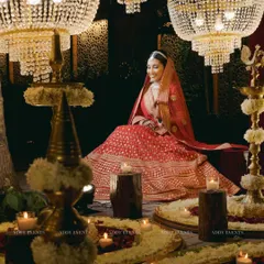 A moment of serene grace. The bride, seated amidst a sea of flowers and candles, is illuminated by the warm glow of crystal chandeliers, creating a truly magical portrait.