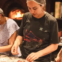 A guest carefully adds toppings to her pizza during one of our workshops. It's a hands-on experience where you get to be the chef.
