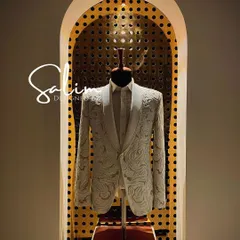 A white tuxedo jacket on display, highlighting the intricate, swirling embroidery that covers the entire piece. This showcases the level of detail I can achieve with threadwork.