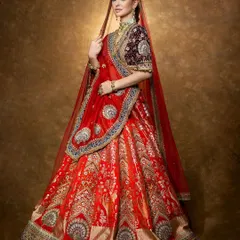 A majestic bridal look featuring a rich red lehenga with a contrasting velvet blouse. This shot captures the full splendor and heritage feel of the design.