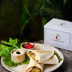 Our finished Falafel Wrap, cut in half to reveal the delicious fillings inside. It's served with hummus and pickled vegetables on the side.