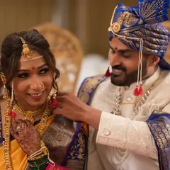 A candid, playful moment as the groom helps the bride with her jewelry. These are the unscripted memories we love to capture during a traditional Marathi wedding.