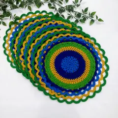 Another view of the stacked peacock placemats, highlighting the scalloped green border that finishes the design.