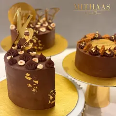 A trio of my rich chocolate cakes, each uniquely decorated. One is topped with Ferrero Rocher and hazelnuts, another with Biscoff cookies, showing the variety of custom designs I can create.
