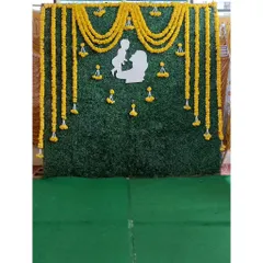 This traditional backdrop is perfect for a baby shower or naming ceremony. It features an artificial green wall decorated with bright yellow marigold garlands and a beautiful white silhouette cutout of a mother and baby.