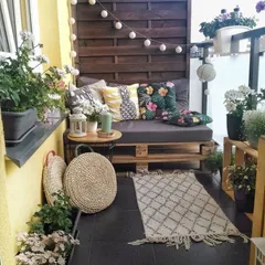 This cozy balcony uses a wooden privacy screen, string lights, and comfortable cushions to create an intimate and inviting outdoor nook, perfect for relaxing.