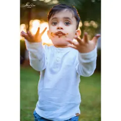 Look at my hands. This is the pure, unscripted joy of a second birthday chocolate cake smash. Ivaan shows off his messy hands against the warm sunset light, creating a perfect candid memory.