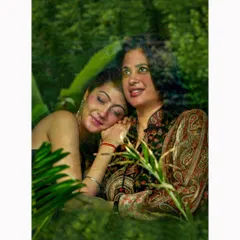 A creative family portrait of a mother and daughter, viewed through a window to create a soft, reflective effect. This technique adds an artistic layer to the image, enhancing the feeling of warmth and tenderness.