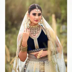 An outdoor bridal shoot capturing a serene and elegant moment. The natural setting complements the traditional lehenga, and the soft lighting highlights the delicate details of the fabric and embroidery.