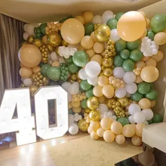 A sophisticated balloon wall in sage green, beige, and gold for a 40th birthday. The large, light-up marquee numbers add a personalized and high-end touch to the celebration.