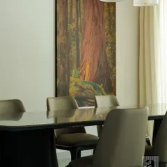 A close-up of a modern dining area I designed. The sleek, dark dining table with its reflective surface is paired with comfortable, contemporary chairs. The large nature-inspired artwork adds a splash of color and personality.