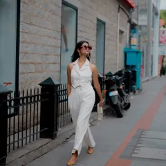 A full-length action shot of a model walking down a city street in a stylish white pantsuit. This type of "paparazzi" style shot is great for creating authentic and aspirational lifestyle content for a fashion blog or brand.