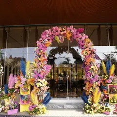 This stunning floral arch is bursting with a rainbow of colors, including bright pinks, yellows, and blues. It serves as a spectacular entrance for a carnival themed corporate event, setting a joyful and energetic tone.