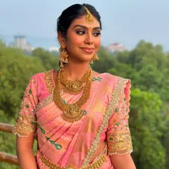 A beautiful smile that lights up the frame. This South Indian bridal look features a soft smokey eye and radiant skin, perfectly complementing her pink Kanjeevaram saree and temple jewelry.
