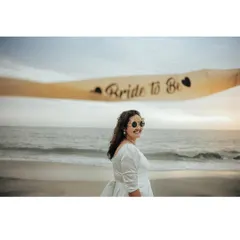 The bride-to-be posing with her sash on the beach, her smile full of excitement.