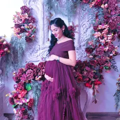 A solo portrait of the mother-to-be, glowing amidst a stunning floral arch. This setup uses a variety of deep red, purple, and pink flowers to create a rich, textured backdrop that makes for unforgettable pregnancy photos.