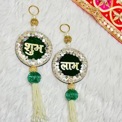 This elegant Shubh Labh latkan set is crafted on a dark green velvet base with sparkling sequin borders. The beaded tassels add a touch of traditional grace.